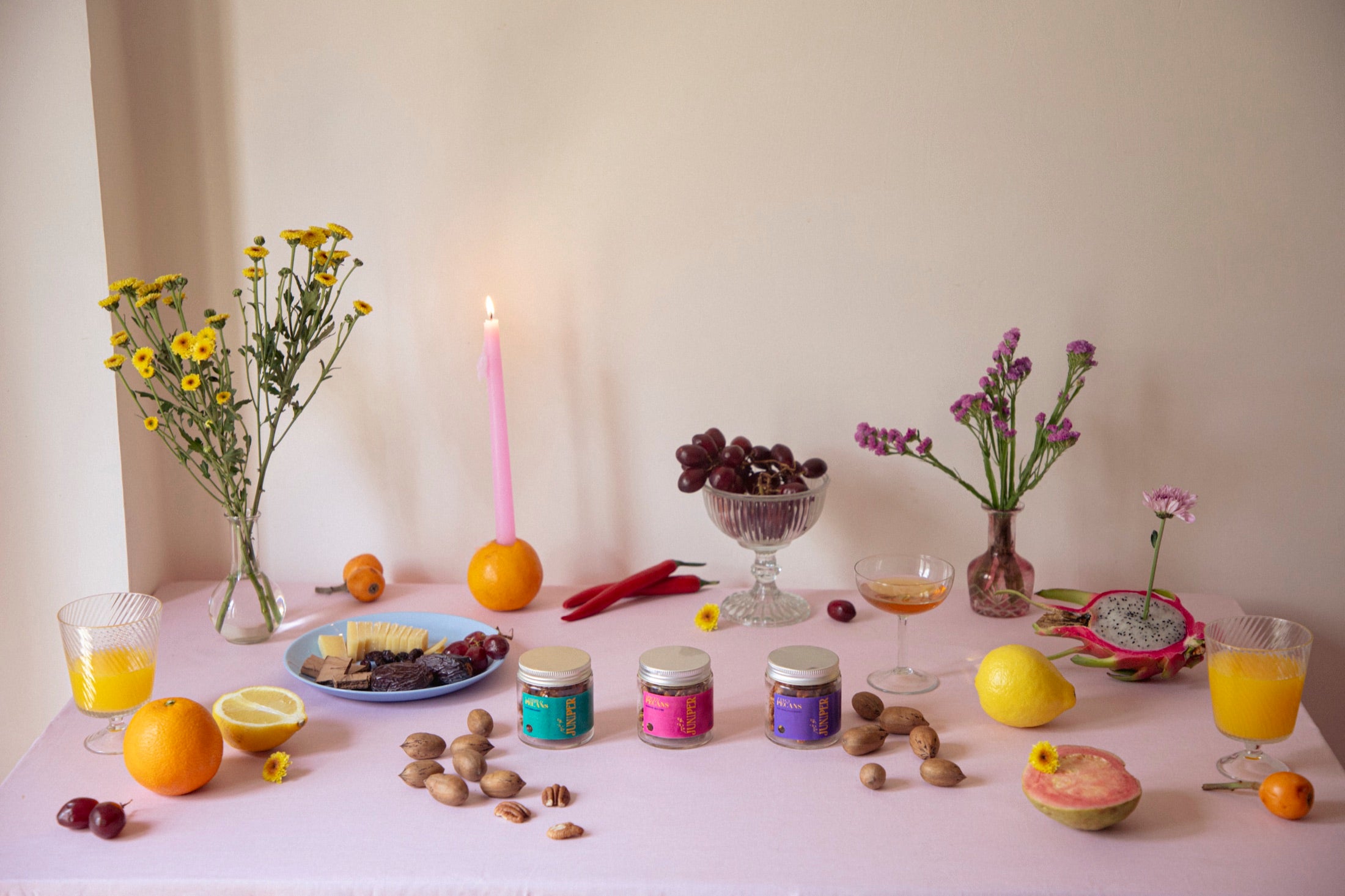 A styled table of Juniper pecans, fruit and flowers