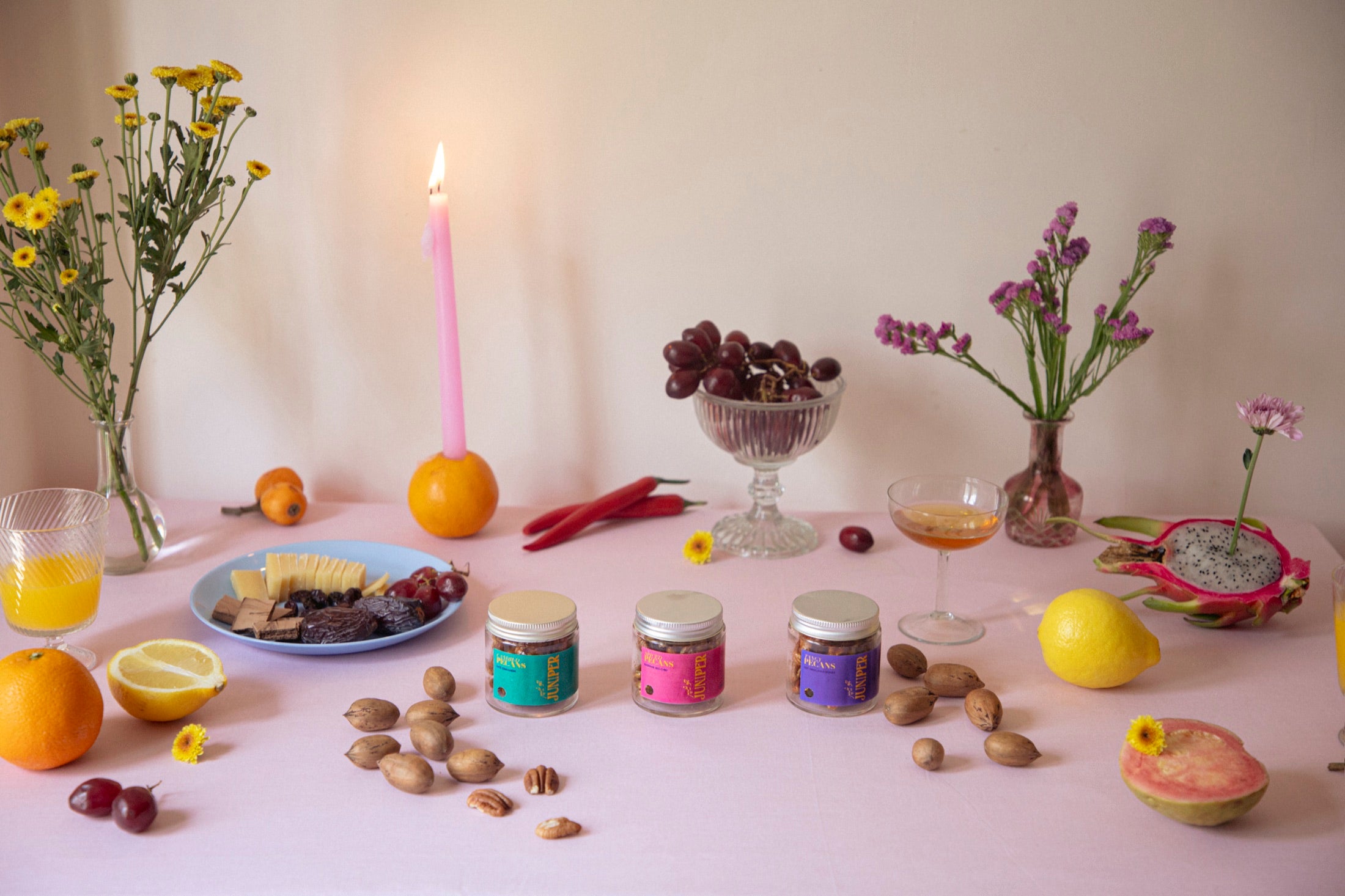 A table spread of Juniper pecan jars with fruit, flowers and a candle
